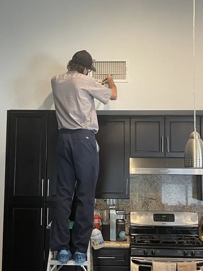 Technician inspecting an air vent during HVAC service in Mequon